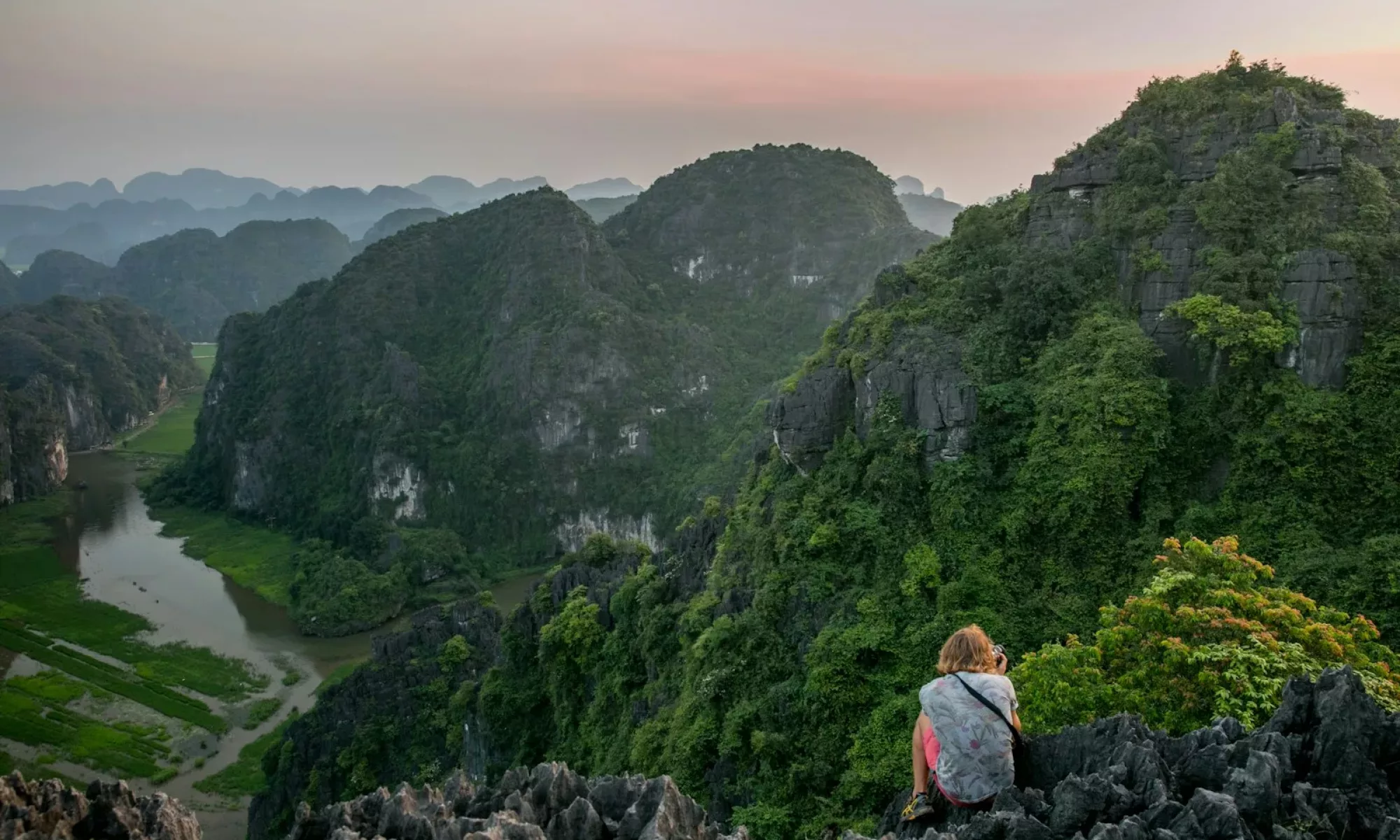 person sitting on cliff during daytime
